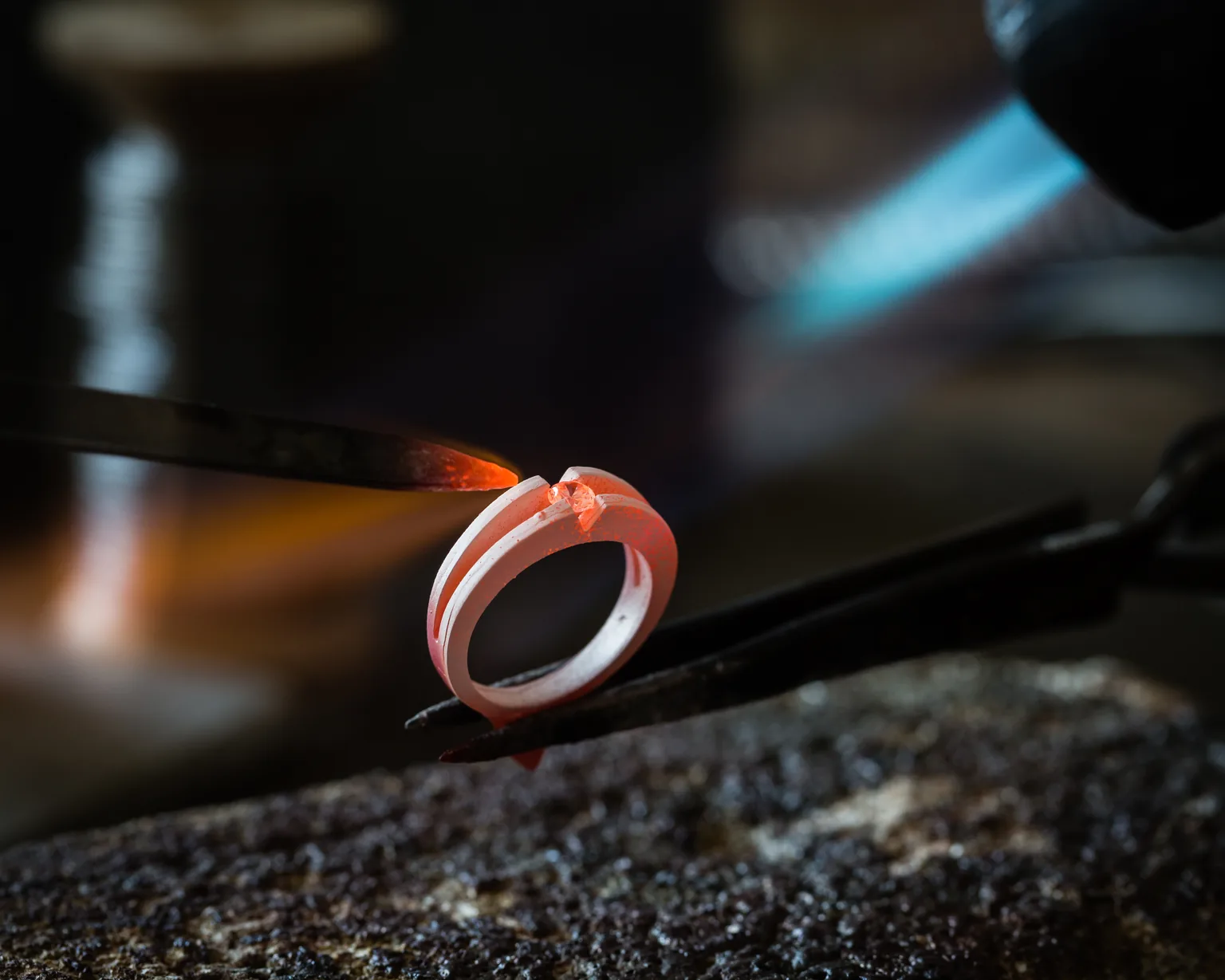 Fassen eines Edelsteins in einen erhitzten Ring in der Goldschmiede Lotos