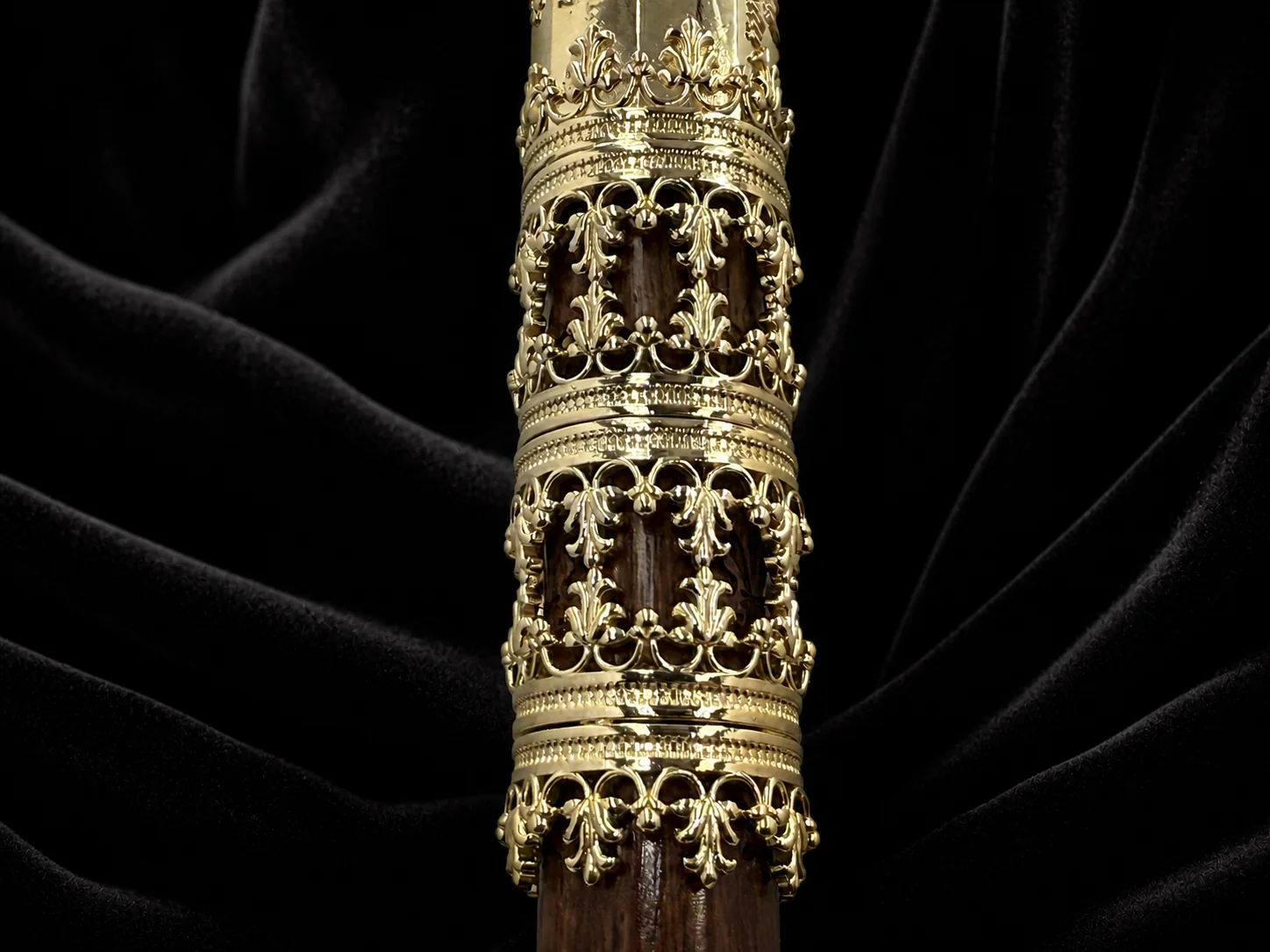 Filigrane Goldornamente mit Lilienmotiven auf dem Nussbaumholz des Familiengehstocks