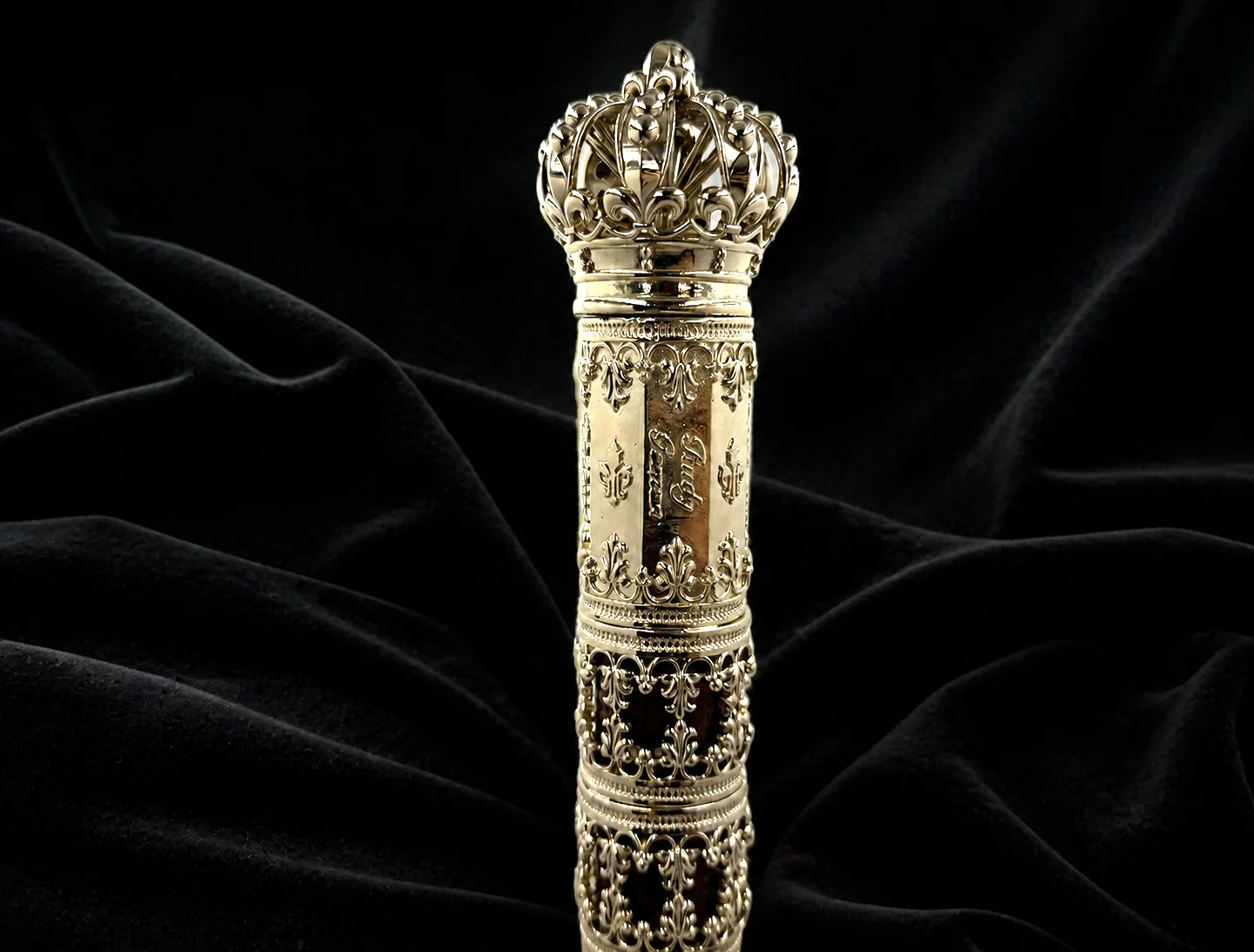 Goldene Krone und filigrane Ornamente am Kopf eines handgefertigten Familiengehstocks aus Nussbaumholz