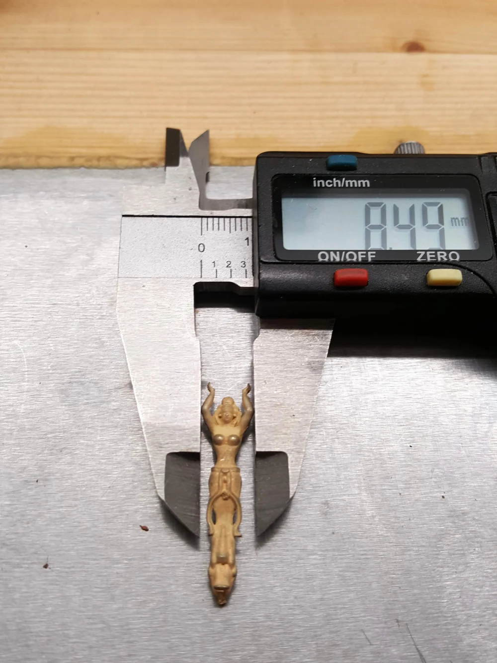 Präzise Vermessung der goldenen Figur mit einem digitalen Messschieber