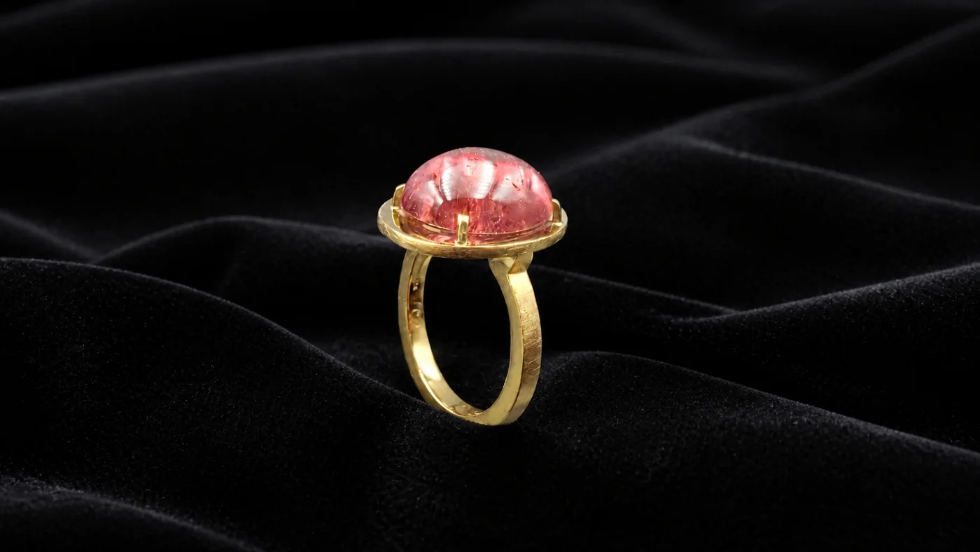 Goldring mit großem rosafarbenem Cabochon auf schwarzem Samt